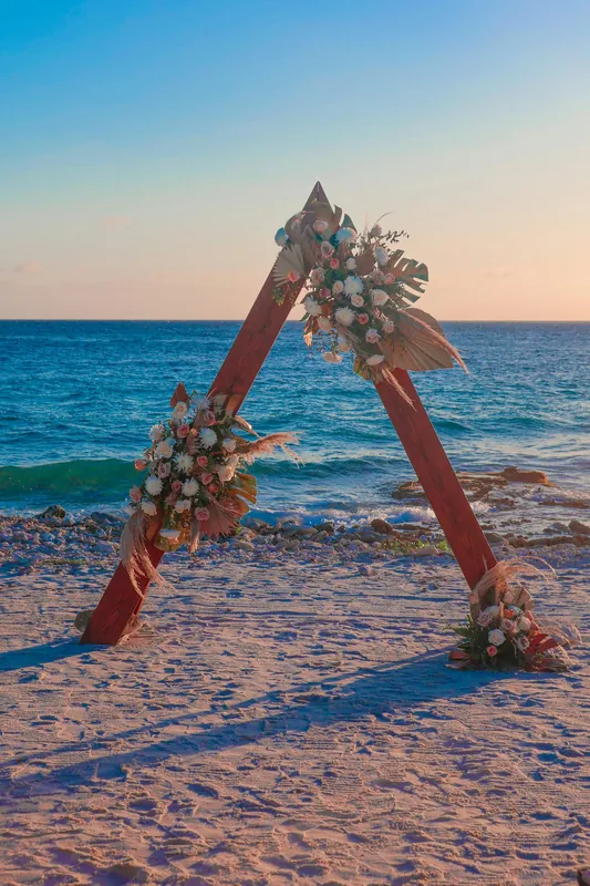 A triangular timber arch and tropical flowers on a Curacao beach