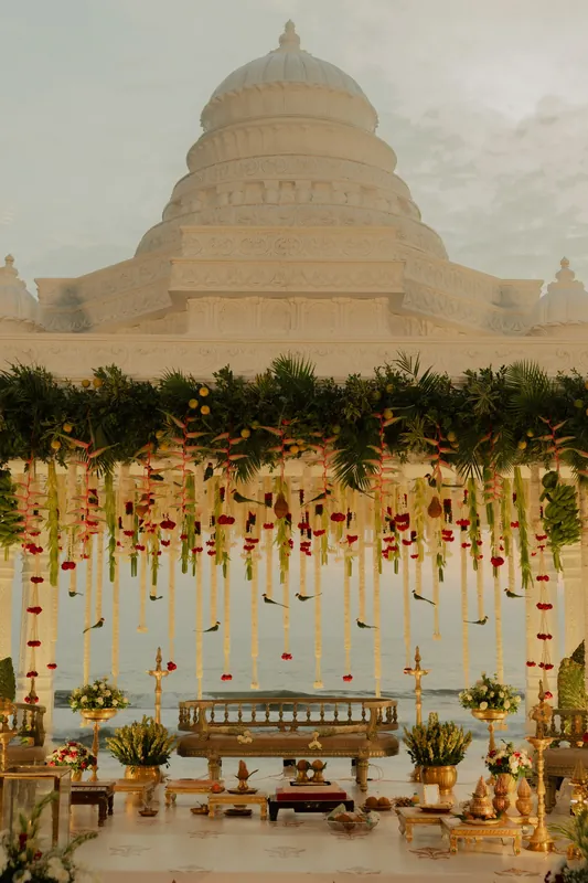 A carved ivory mandap with floral garlands and brass vessels in India